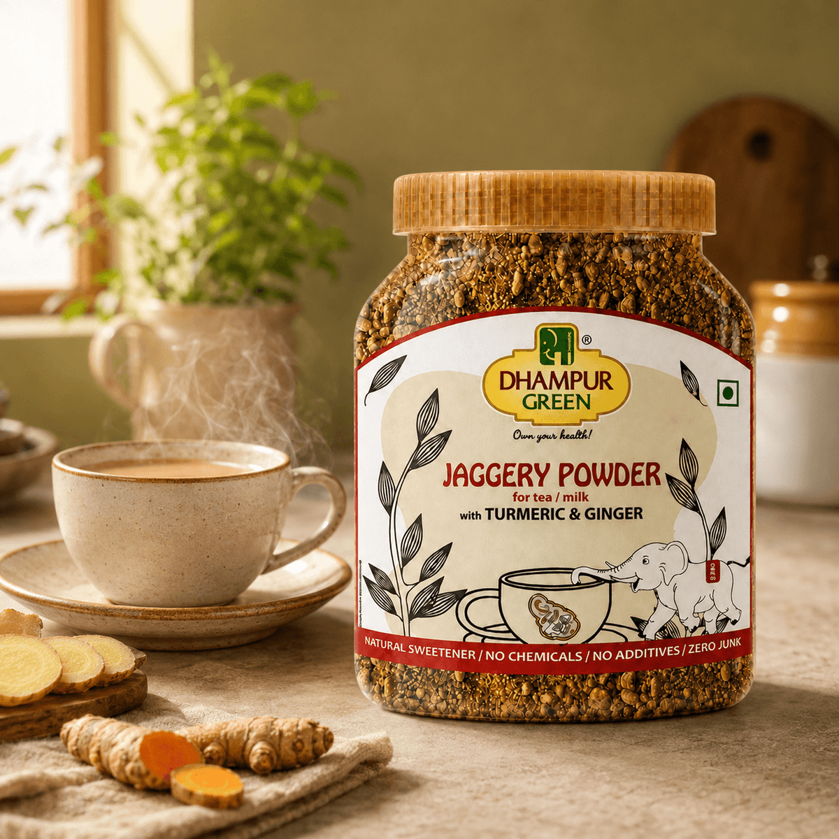 A jar of Dhampur Green Jaggery Powder with Turmeric & Ginger is shown on a rustic tabletop next to a cup of tea, ginger roots, turmeric slices, and a potted plant in the background.