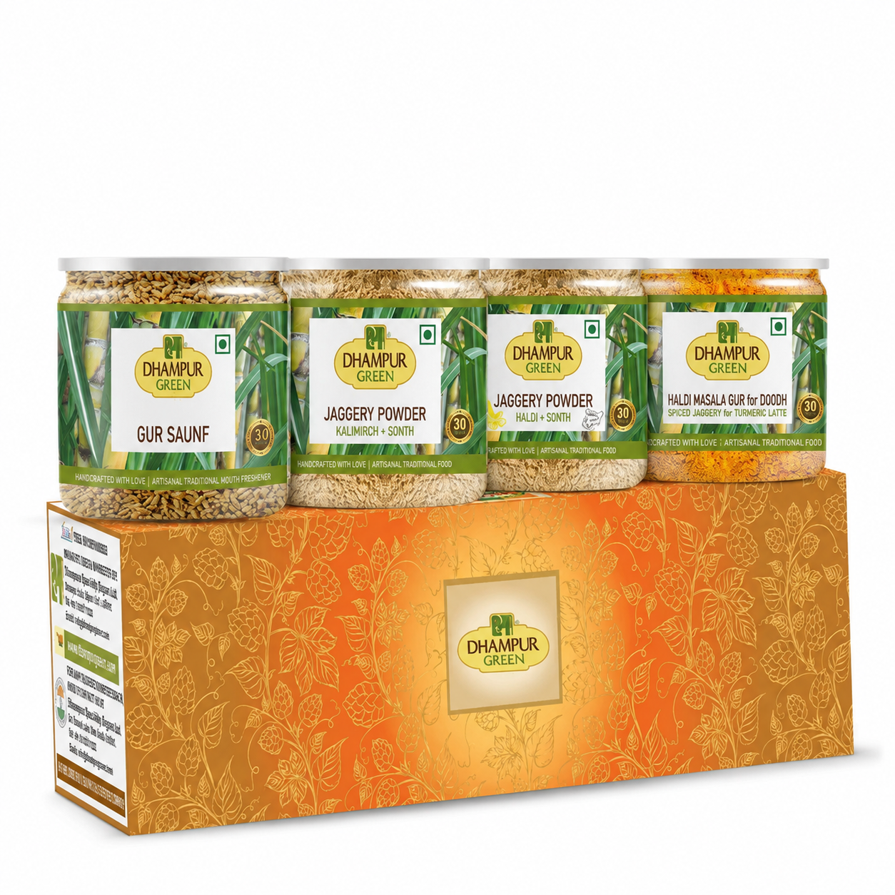 A Dhampur Green gift set containing four jars of spices (Gur Saunf, Jaggery Powder, Malai Chutney, and Phalodi Masala Guri) arranged on top of an orange patterned box.