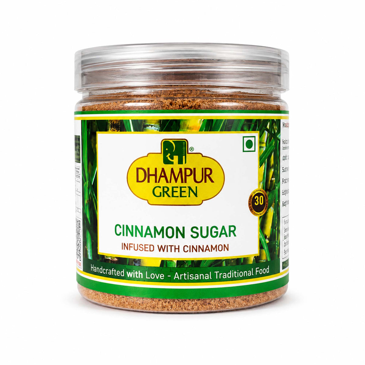 A jar of Dhampur Green Cinnamon Sugar on a white background. The product is in a clear plastic jar with a green and yellow label, showing the brown cinnamon sugar inside.